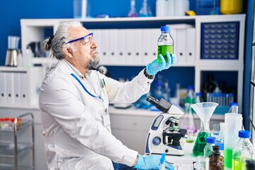 Wall Mural - Middle age grey-haired man scientist looking bottle at laboratory