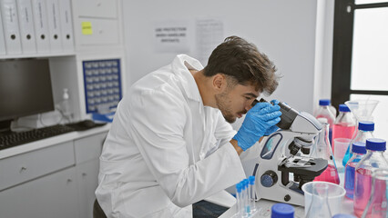 Wall Mural - Young arab man scientist using microscope at laboratory