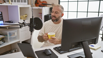 Charming young man reporter broadcasting live radio show, enjoying morning espresso indoors at vibing  radio studio