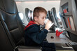 A little boy on board the plane eats chocolate candies while drinking water