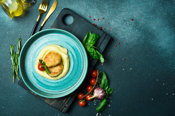 Wall Mural - Mashed potatoes with chicken cutlet. On a plate. Restaurant dishes. On a dark stone background.