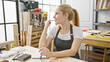 © Krakenimages.com - A contemplative young blonde woman in a workshop filled with carpentry tools and wood.