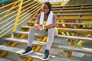 Canvas Print - African american woman using stopwatch sitting on stairs at street