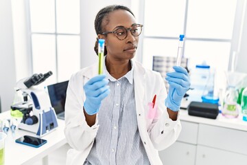 Canvas Print - African american woman scientist holding test tubes at laboratory