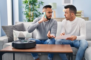 Canvas Print - Two men talking on smartphone with technician vacuum robot service at home