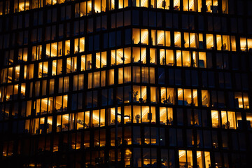 Wall Mural - Office building exterior with glowing lights in windows at night city. Vienna city downtown district with skyscraper facades. Night city panorama. Working late at corporation