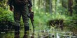 © koldunova - Hunter standing in the swamp in the forest and holding in his hand hunting rifle , concept of Woodland environment