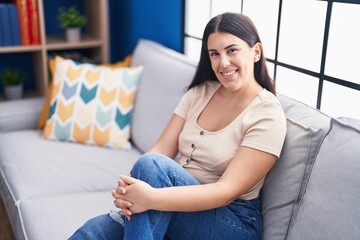 Sticker - Young beautiful hispanic woman smiling confident sitting on sofa at home