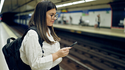 Sticker - Young beautiful hispanic woman waiting for the subway using smartphone in subway station of Madrid