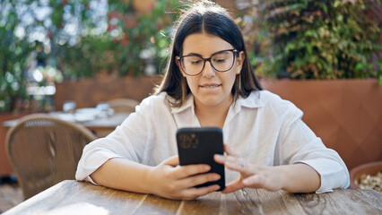 Canvas Print - Young beautiful hispanic woman smiling happy using smartphone sitting on the table at bar terrace