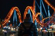 solo visitor watching illuminated roller coaster