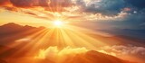 Fototapeta Zachód słońca - A photo capturing the golden rays of the sun shining through a cloudy sky as it sets over a majestic mountain range.