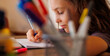 © zhukovvvlad - Side view of a focused little boy who is learning to write while doing his homework while sitting at his desk at home. Portrait of a smart preschooler who is learning to write. writing training.