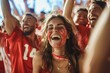 A jubilant woman adorned with vibrant red paint on her beaming face stands out among a sea of cheering festival-goers, her clothing and smile reflecting the lively outdoor music event