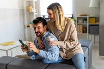 Wall Mural - Happy young couple, woman and man hugging, using smartphone together. Social media concept.