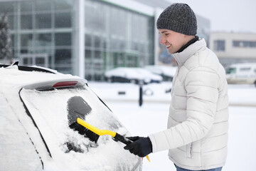 Canvas Print - Man cleaning snow from car window outdoors