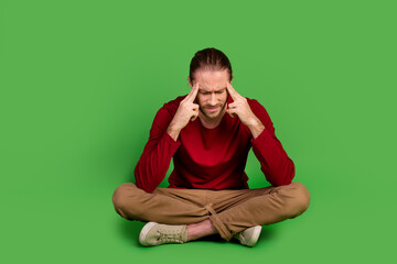 Poster - Full size photo minded pensive guy wear red shirt brown trousers sit on floor think solution of problem isolated on green color background