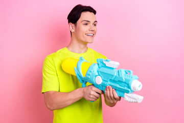 Photo portrait of nice teen man point hold water gun shopping poster dressed stylish yellow clothes isolated on pink color background