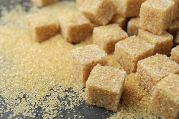 Brown sugar cubes on grey table, closeup