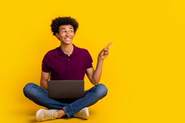 Photo of cheerful man wear trendy violet clothes sit floor look empty space recommend buy novelty isolated on yellow color background