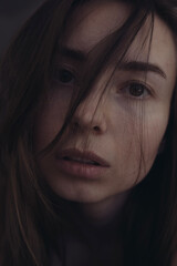 Portrait photo of a woman without makeup. Hair covering a woman's face. Emotional photo of a woman.  The concept of anxiety and asking for help. Stressed woman.
