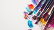 An arrangement of colorful paintbrushes dipped in various hues of paint on a pristine white surface