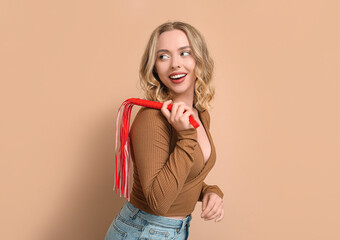 Wall Mural - Beautiful young woman with whip on beige background