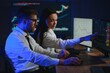 © Serhii - Team of stockbrokers are having a conversation in a dark office with display screens