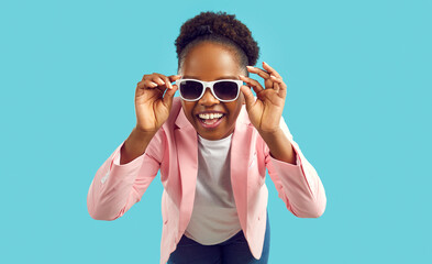 Wall Mural - Portrait of happy beautiful woman in stylish outfit. Cheerful young African American girl wearing fashionable pink jacket and cool trendy sunglasses looking at camera and smiling. Fashion concept