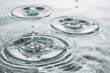 Poster - A captivating close-up shot of three glistening water droplets suspended in a sink, reflecting light and creating a mesmerizing pattern of ripples