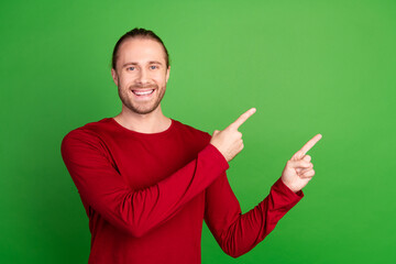 Wall Mural - Photo of positive man with stubble long hairdo dressed red pullover indicating at promo empty space isolated on green color background
