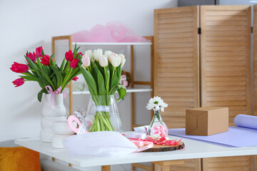 Sticker - Gift box, packing materials and beautiful flowers on light table in room. International Women's Day