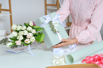 Wall Mural - Woman with beautiful gift box, packing materials and flowers for International Women's Day at light table