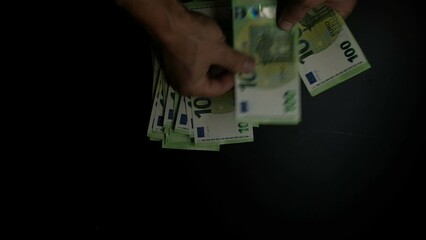 Wall Mural - Male hands counting a large stack of euro bills, close-up on a dark background