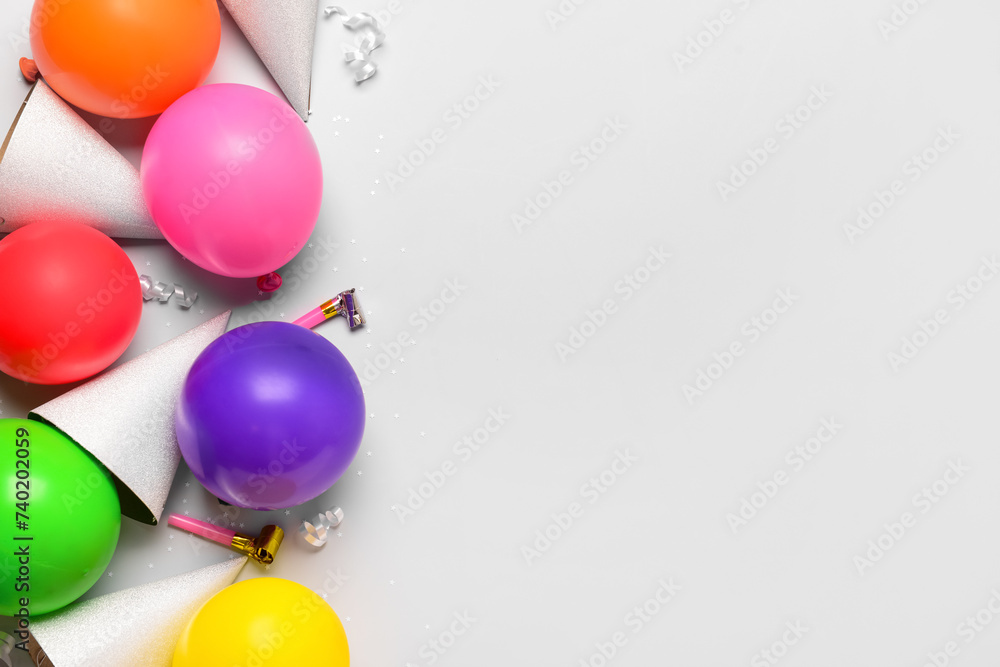 Composition with party hats, balloons and noisemakers on white background