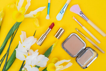 Wall Mural - Minimal modern cosmetic scene with set of make up brushes, cosmetics and flowers set over yellow background