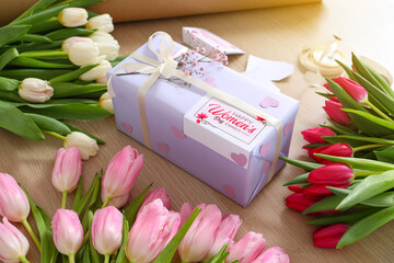 Sticker - Gift box and beautiful tulip flowers for International Women's Day on wooden table