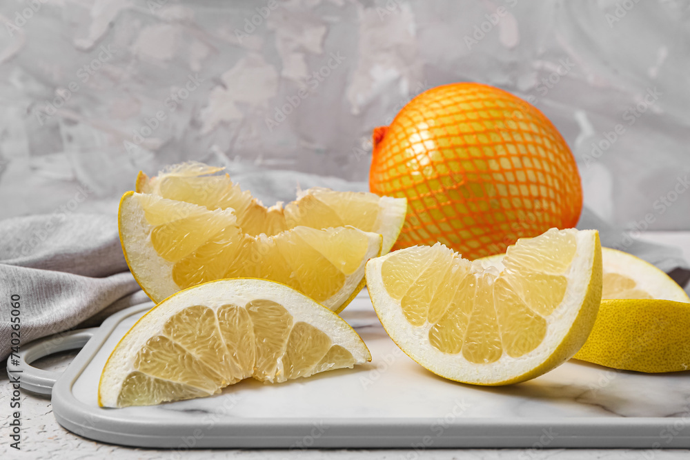 Tasty pomelo fruit in net and board with slices on white table