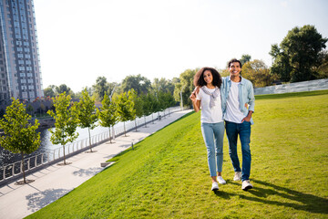 Canvas Print - Full body portrait of cheerful peaceful soulmates hold arms cuddle walk green grass city center outside