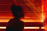 Fototapeta Tulipany - A woman sitting in a sauna room with a red light. Infrared sauna interior