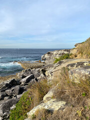 Wall Mural - The coast of the sea. Mountains cliff in the ocean. View of the rocky coast of island, Australia. Waves curling on the rocky shore.