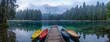 Colorful canoes rest on calm lake, misty forest backdrop and mountain beyond