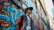 A fashionable young man in a red beanie and jacket stands confidently against a vibrant backdrop of urban street art and graffiti..