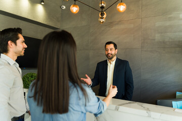 Wall Mural - Male receptionist greeting some businesspeople in an office