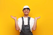 © Богдан Маліцький - asian male builder in uniform holding empty hands on yellow isolated background