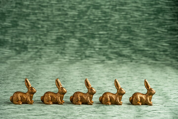 Canvas Print - Row of decorative gold bunnies on a textured green velvet background, Happy Easter
