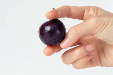 Hand holding acai berry isolated on gray background, healthy fruit food