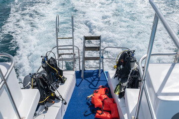 Diving equipment with oxigen tanks and fins sitting at the back of the tour boat. Active vacation, south destination travel concept. 