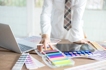 Graphic designer using color swatch to do his work at modern office. Architect using work tools and sample colour catalog.