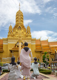 Fototapeta Londyn - Golden designed buddhist temple architecture pagoda and standing buddha meditation statues  at the Ancient City Siam Bangkok historical museum site.